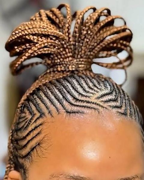 Zig-zag cornrows at the front leading into a looped top knot